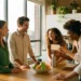 Diverse collega's rond een zonnige kantinetafel delen een beloningskaart, met vers fruit en een herbruikbare fles op tafel.
