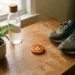 Gloeiende amberen munt op houten bureau, omringd door welzijnsobjecten: waterfles, loopschoenen en groene plant in warm natuurlijk licht.