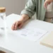 HR-professional bestudeert organisatieschema aan minimalistisch bureau met plant, notitieboek en waterfles in rustgevende groene en ivoren tinten.