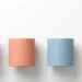 Vier pastelkleurige stenen pilaren in salie, koraal, lichtblauw en amber op wit oppervlak, bovenaanzicht, minimalistische compositie.